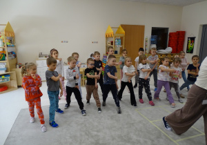 32 Dzieci z panią podczas zabawy muzyczno - ruchowej utrwalającej kierunki w przestrzeni i stronności własnego ciała