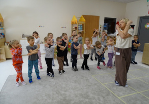33 Dzieci z panią podczas zabawy muzyczno - ruchowej utrwalającej kierunki w przestrzeni i stronności własnego ciała