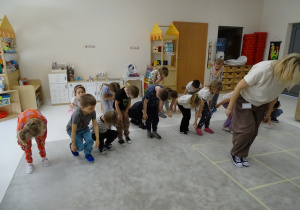 34 Dzieci z panią podczas zabawy muzyczno - ruchowej utrwalającej kierunki w przestrzeni i stronności własnego ciała