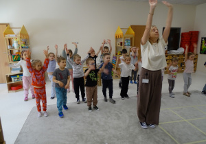45 Dzieci z panią podczas zabawy muzyczno - ruchowej utrwalającej kierunki w przestrzeni i stronności własnego ciała
