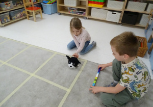 53 Dziewczynka ustawia pieska w kierunku, który pokazuje chłopiec za pomocą strzałki