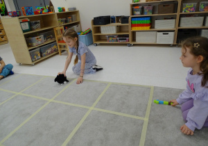 57 Dziewczynka ustawia pieska w kierunku, który pokazuje druga dziewczynka za pomocą strzałk