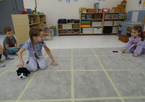 58 Dziewczynka ustawia pieska w kierunku, który pokazuje druga dziewczynka za pomocą strzałk