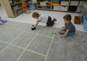 59 Dziewczynka ustawia pieska w kierunku, który pokazuje druga dziewczynka za pomocą strzałk