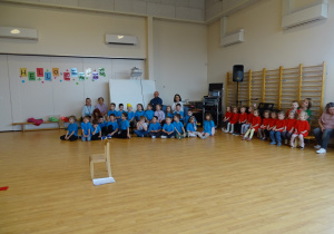 dzieci siedzą na sali gimnastycznej