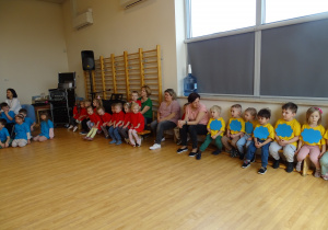 dzieci siedzą na sali gimnastycznej