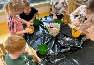 dzieci wsypują ziemię do donic