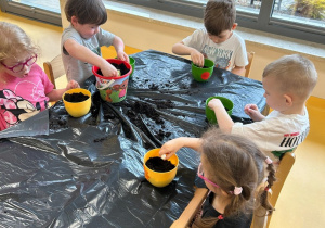 dzieci wsypują ziemię do donic