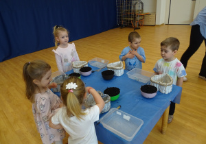 dzieci dekorują pojemnik ziemią