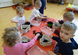 dzieci dekorują pojemnik ziemią
