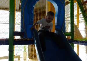 chłopiec zjeżdża na zjeżdżalni