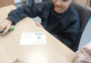 Dziewczynka prezentuje, jak ozdobiła pocztówkę