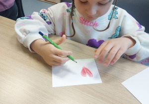 Dziewczynka rysuje serce na pocztówce