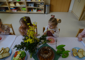dzieci siedzą przy stole i jedzą śniadanie wielkanocne