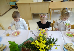 dzieci siedzą przy stole i jedzą śniadanie wielkanocne