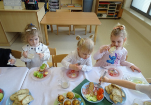 dzieci siedzą przy stole i jedzą śniadanie wielkanocne