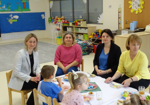 panie z dziećmi siedzą przy stole i jedzą śniadanie wielkanocne