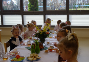 dzieci siedzą przy stole i jedzą śniadanie wielkanocne