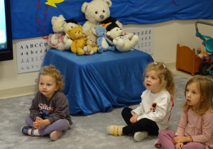 Dziewczynki na tle maskotek ćwiczą język