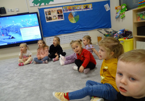 Dzieci siedząc w kole doklejają język do podniebienia