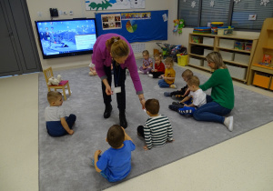 Logpedka rozdaje dzieciom wycięte chmurki do ćwiczeń oddechowych