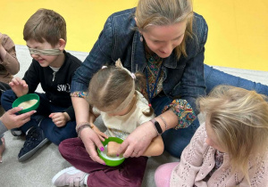 Dziewczynka i chłopiec z zasłoniętymi oczyma odgadują, jakiego produktu dotykaja