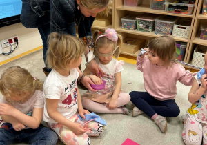 Logopeda podaje pojemniczek z produktami kolejnej dziewczynce