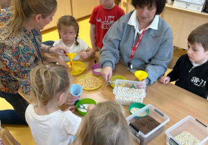 Nauczycielka i logopedka pomagają dzieciom wykonać gniotki z wybranymi produktami spożywczymi