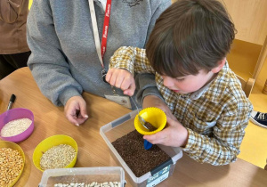 Chłopiec pod okiem nauczycielki wykonuje gniotka, wsypując do balonika len