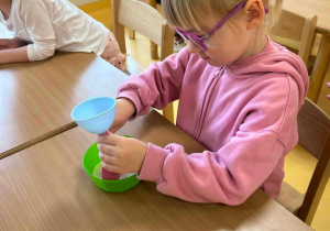 Dziewczynka wsypuje przez lejek cukier do różowego balonika