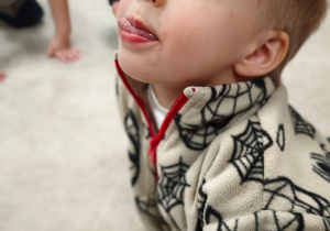 Chłopiec chowa język za zębami górnymi