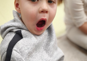 Chłopiec prezentuje ułożenie ust do samogłoski A