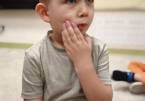 Chłopiec wskazuje ułożenie języka na policzku