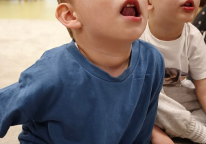 Chłopiec unosi język za zęby górne