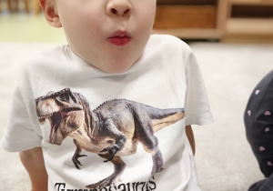 Chłopiec masuje policzki, by znaleźć bajkowego dinozaura