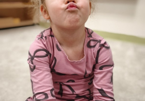 Dziewczynka wysuwa złączone wargi do przodu