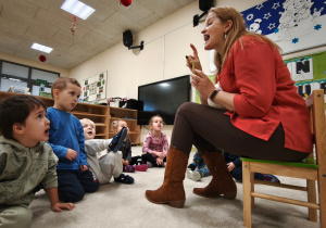 Logopeda pokazuje przed dziećmi kolejne ćwiczenie języka