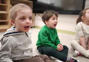 Dzieci unoszą na przemian język za zęby górne i układają go na brodę