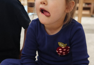 Dziewczynka układa język w kąciku ust