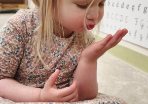 Dziewczynka wydmuchuje na dłoń strumień powietrza