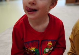 Chłopiec układa język w kąciku ust