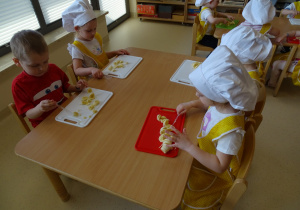 dzieci kroją owoce na desce