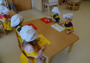 dzieci kroją owoce na desce