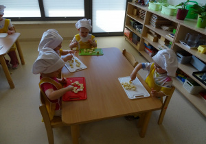 dzieci kroją owoce na desce