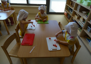 dzieci kroją owoce na desce