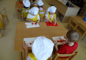 dzieci kroją owoce na desce