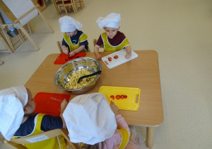 dzieci kroją owoce na desce