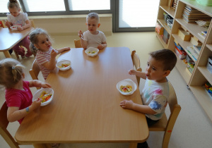 dzieci jedzą sałatkę owocową