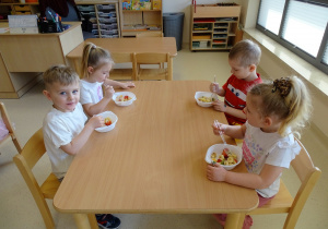 dzieci jedzą sałatkę owocową