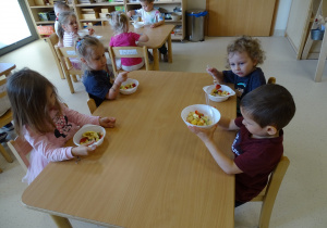 dzieci jedzą sałatkę owocową